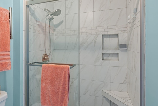 bathroom featuring a shower with door and toilet