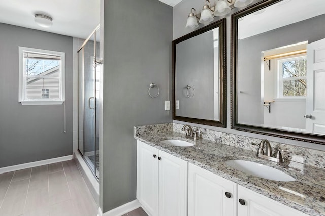 bathroom featuring a shower stall, baseboards, and a sink