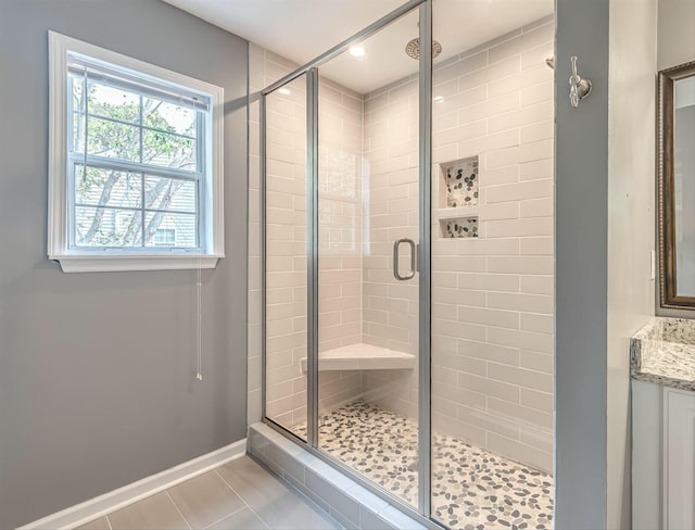 bathroom featuring a stall shower, vanity, baseboards, and tile patterned floors