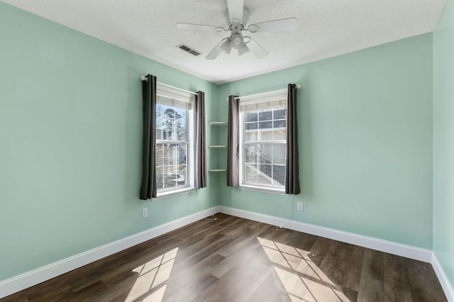 spare room with dark wood-style floors, visible vents, ceiling fan, and baseboards