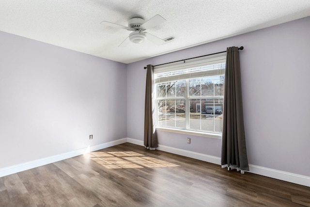 spare room featuring a ceiling fan, wood finished floors, visible vents, and baseboards