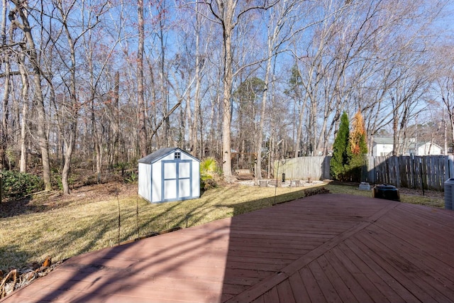 wooden terrace featuring a storage shed, an outbuilding, fence, a yard, and central AC