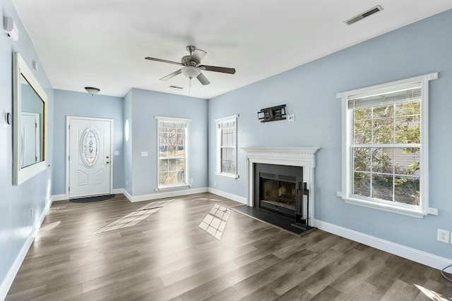 unfurnished living room featuring dark wood-style floors, a wealth of natural light, and visible vents