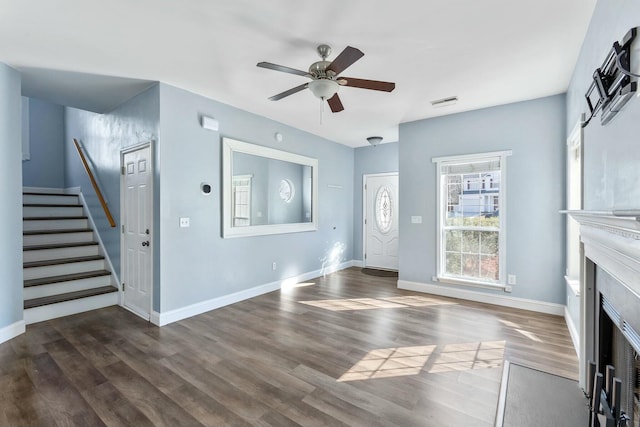 unfurnished living room with wood finished floors, a fireplace with flush hearth, a ceiling fan, stairs, and baseboards