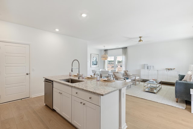 kitchen featuring recessed lighting, a sink, open floor plan, stainless steel dishwasher, and light wood-type flooring