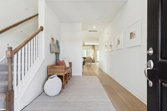 foyer entrance with visible vents, stairway, baseboards, and light wood-style floors