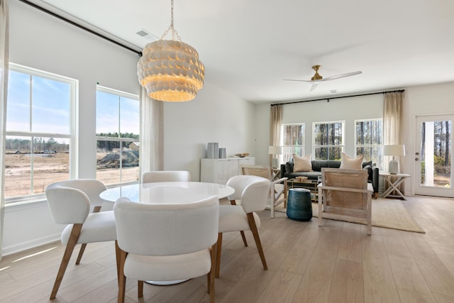 dining area with visible vents, baseboards, light wood-style flooring, and ceiling fan with notable chandelier