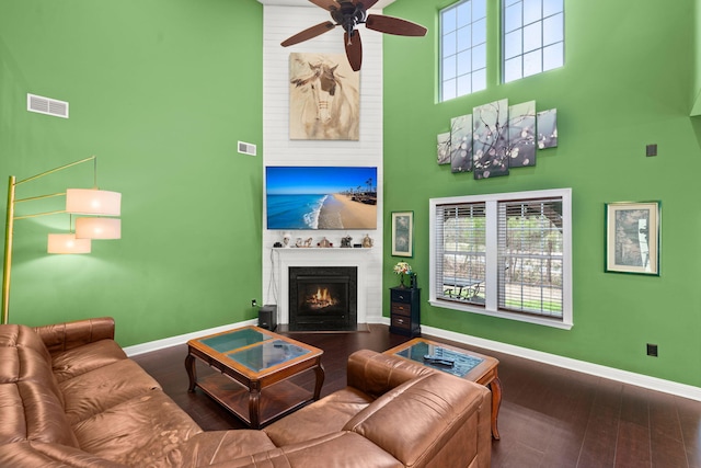 living room with a towering ceiling, visible vents, a wealth of natural light, and wood finished floors