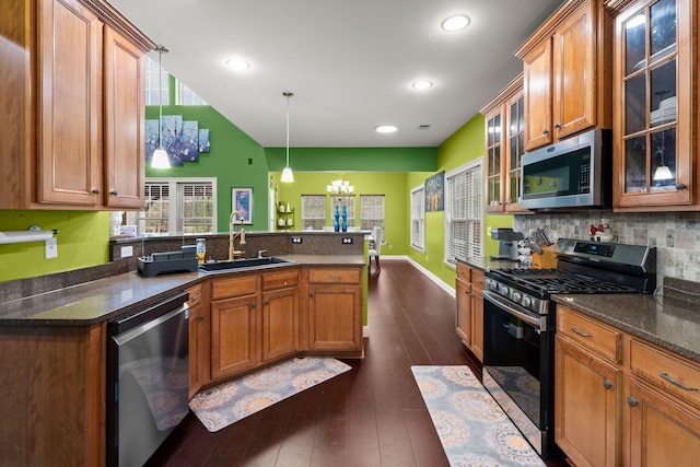 kitchen featuring stainless steel appliances, brown cabinets, a sink, and a peninsula