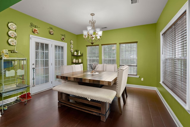 dining area featuring visible vents, a notable chandelier, baseboards, and wood finished floors