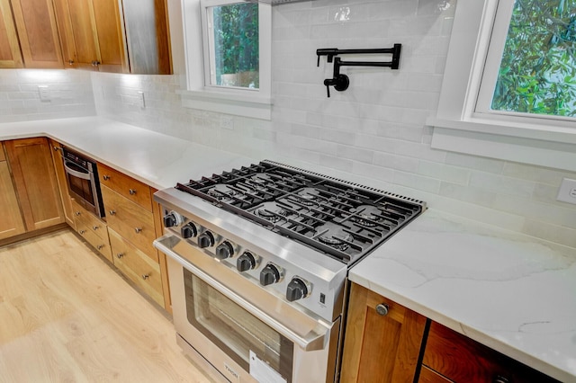 501 Joseph St, Charleston, SC 29412 - kitchen with stainless steel range, backsplash, light wood finished floors, and light stone counters