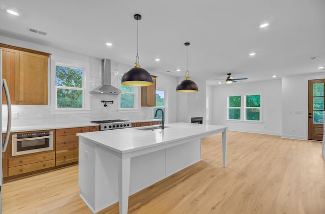 501 Joseph St, Charleston, SC 29412 - kitchen with wall chimney exhaust hood, decorative backsplash, light wood-style flooring, a ceiling fan, and light countertops