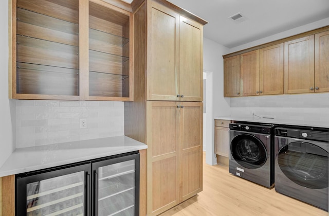 501 Joseph St, Charleston, SC 29412 - laundry room featuring cabinet space, washing machine and clothes dryer, light wood-style floors, and wine cooler