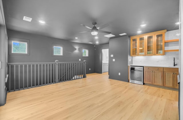 501 Joseph St, Charleston, SC 29412 - kitchen with stainless steel dishwasher, brown cabinetry, light wood finished floors, a ceiling fan, and glass insert cabinets