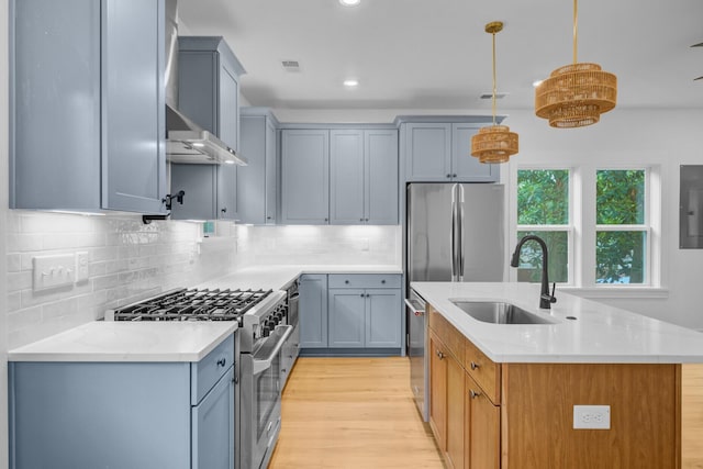 501 Joseph St, Charleston, SC 29412 - kitchen featuring appliances with stainless steel finishes, light wood-style flooring, light countertops, a kitchen island with sink, and decorative backsplash
