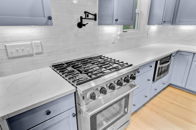 501 Joseph St, Charleston, SC 29412 - kitchen featuring appliances with stainless steel finishes, tasteful backsplash, light stone counters, and light wood-style floors