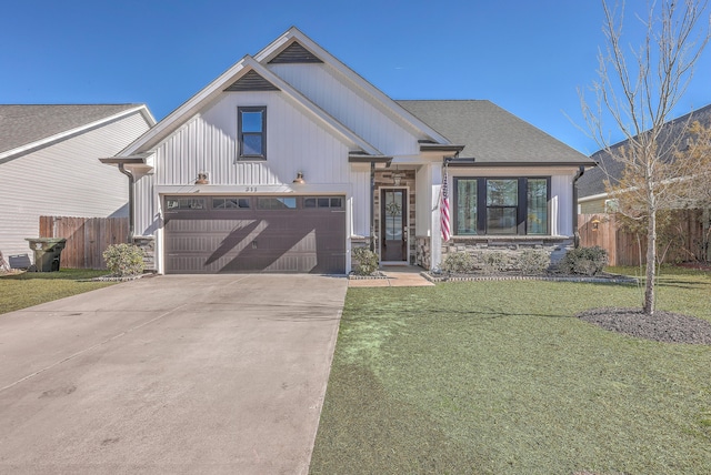 view of front of property with fence, concrete driveway, a front lawn, a garage, and stone siding