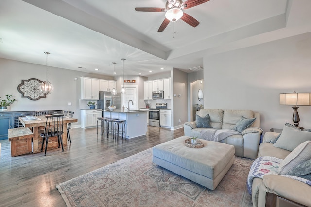 living area with recessed lighting, a tray ceiling, and wood finished floors