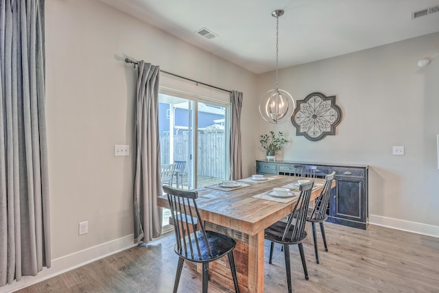 dining space featuring light wood-style flooring, a notable chandelier, and visible vents