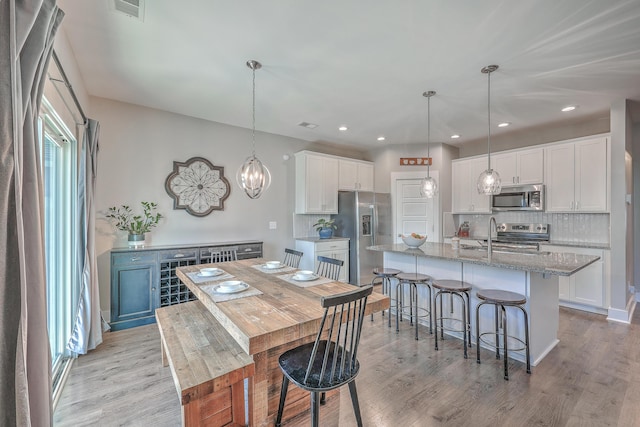 kitchen with tasteful backsplash, light wood-type flooring, and appliances with stainless steel finishes