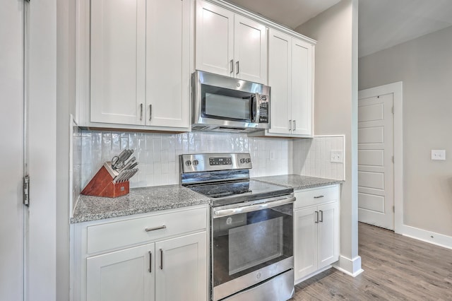 kitchen featuring stone counters, light wood finished floors, stainless steel appliances, decorative backsplash, and white cabinetry