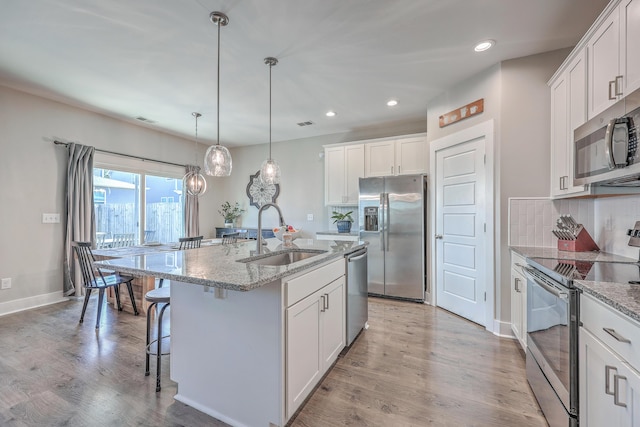 kitchen with a sink, light wood-type flooring, tasteful backsplash, and stainless steel appliances