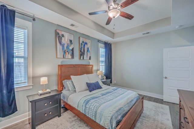 bedroom featuring visible vents, multiple windows, and a tray ceiling