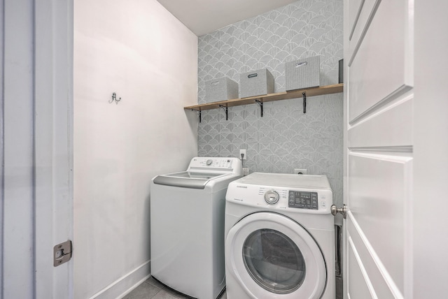 laundry area featuring washing machine and clothes dryer, wallpapered walls, an accent wall, baseboards, and laundry area