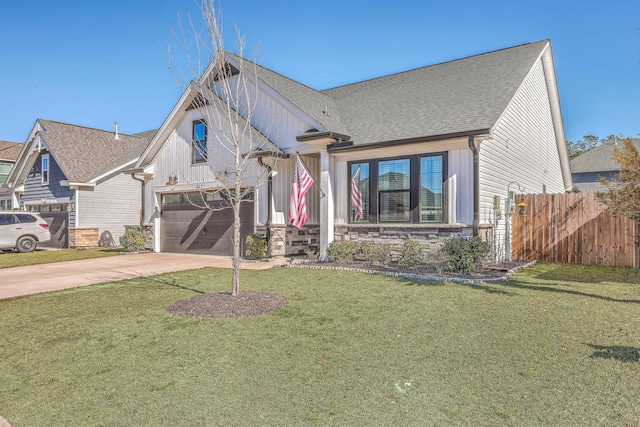 view of front of home featuring a front lawn, driveway, stone siding, fence, and a garage