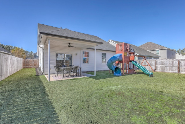 rear view of property featuring a patio, a playground, a yard, and a fenced backyard