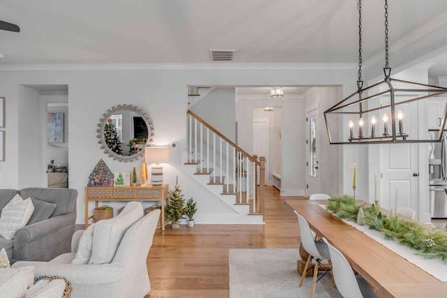 living room with a notable chandelier, light hardwood / wood-style floors, and ornamental molding