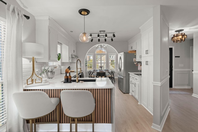 kitchen featuring tasteful backsplash, white cabinetry, an inviting chandelier, a peninsula, and light countertops