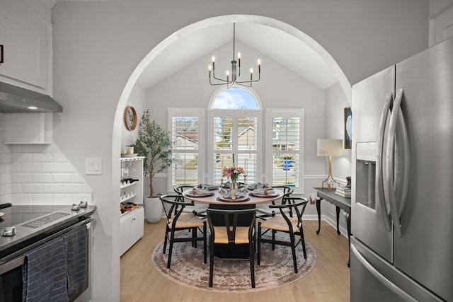 dining space with an inviting chandelier, arched walkways, and light wood-type flooring