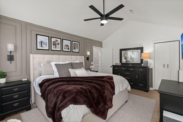 bedroom with light wood finished floors, visible vents, ceiling fan, vaulted ceiling, and a decorative wall