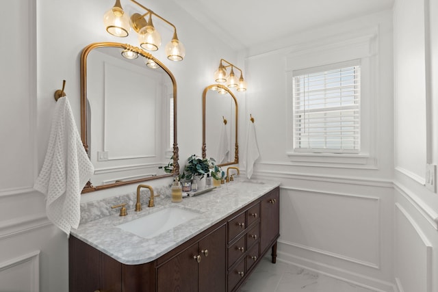 full bathroom featuring double vanity, marble finish floor, wainscoting, and a sink