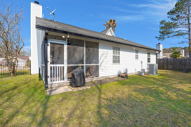 rear view of house featuring central air condition unit, a sunroom, a fenced backyard, a yard, and a ceiling fan