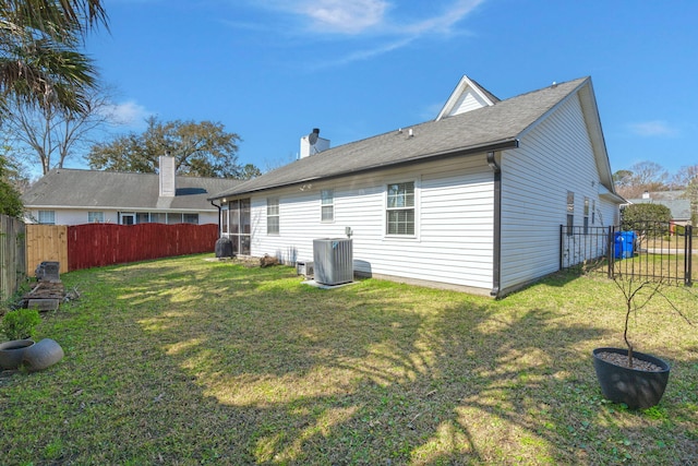 rear view of house featuring a yard, central AC unit, a fenced backyard, and a chimney