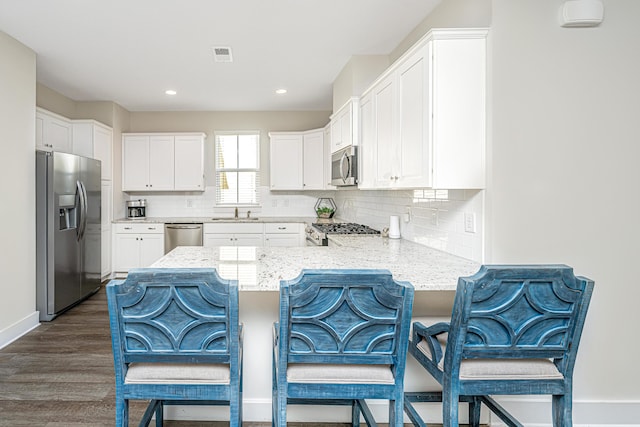 kitchen with visible vents, white cabinets, dark wood finished floors, appliances with stainless steel finishes, and a peninsula