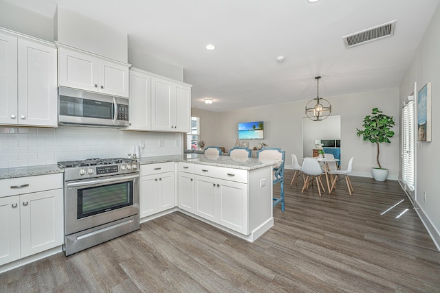 kitchen featuring visible vents, appliances with stainless steel finishes, dark wood-style flooring, a peninsula, and white cabinetry