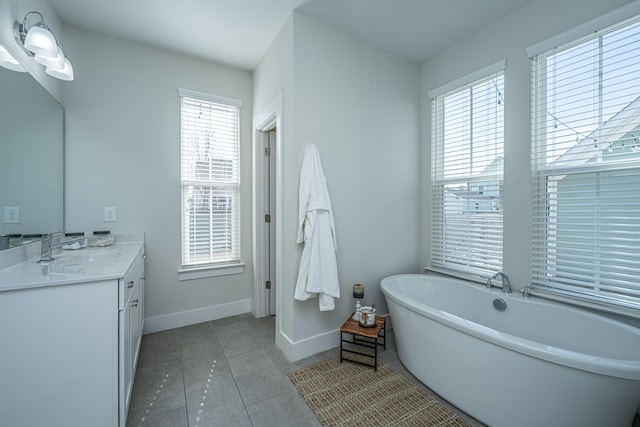 bathroom featuring a freestanding tub, tile patterned flooring, vanity, and baseboards