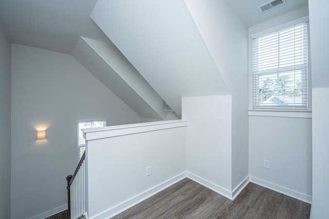 additional living space with lofted ceiling, visible vents, baseboards, and wood finished floors