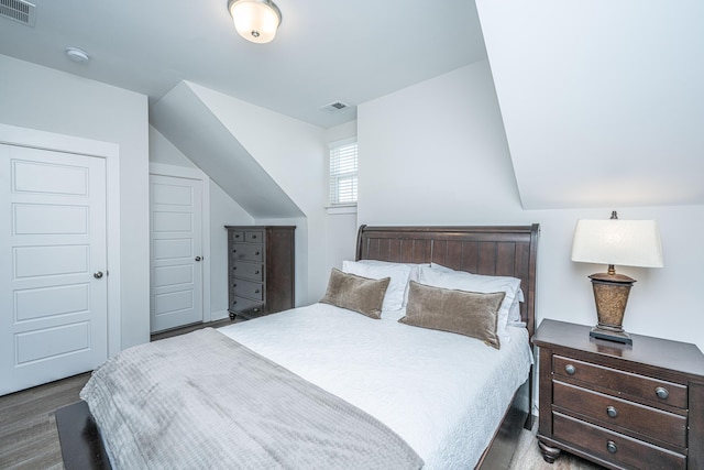 bedroom with visible vents, vaulted ceiling, and wood finished floors