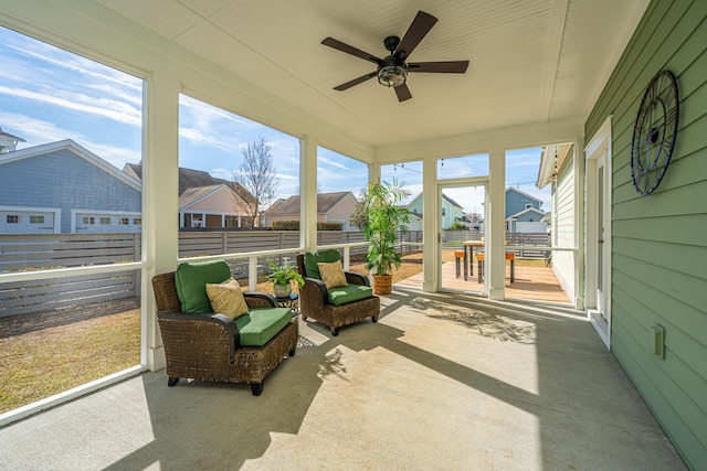 sunroom / solarium featuring ceiling fan, a residential view, and a healthy amount of sunlight