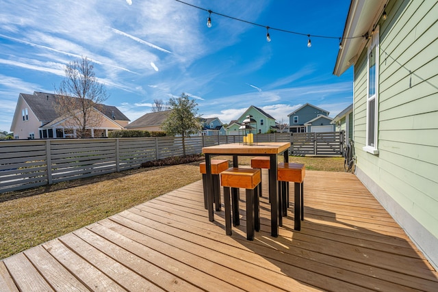 wooden terrace featuring outdoor dining space, a fenced backyard, and a residential view