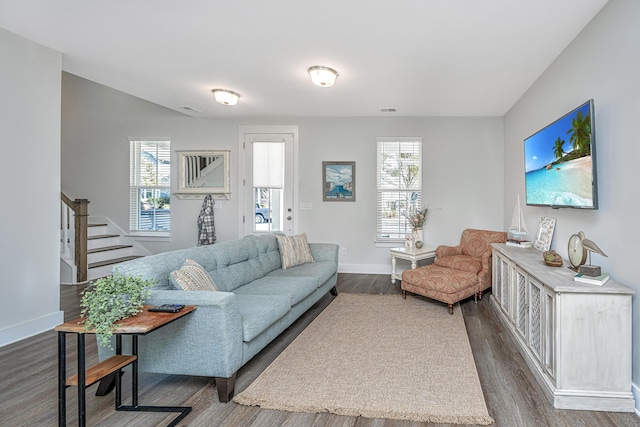 living area with dark wood-type flooring, plenty of natural light, stairway, and baseboards