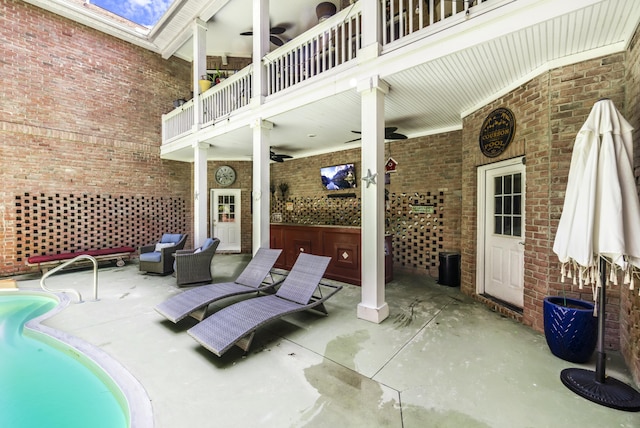 view of patio with ceiling fan and a balcony