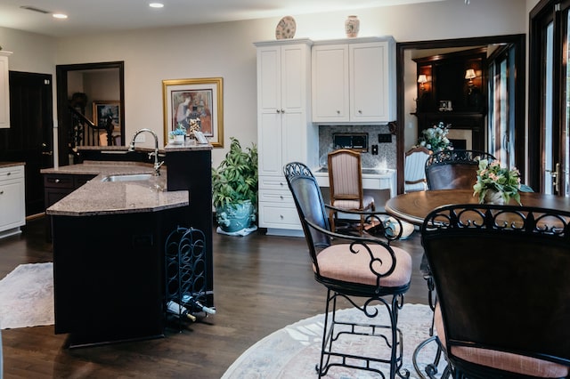 2860 Old Drake Dr, Johns Island, SC 29455 - kitchen featuring light stone countertops, sink, dark hardwood / wood-style flooring, a kitchen island with sink, and white cabinets