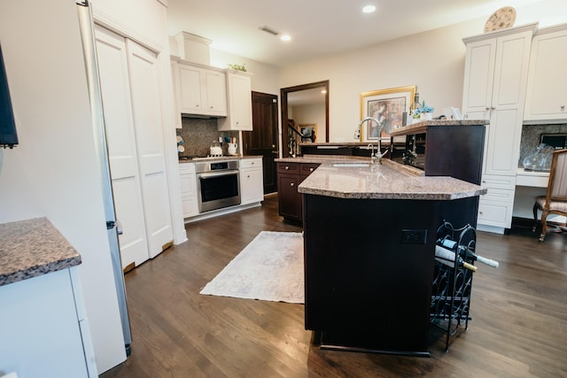 2860 Old Drake Dr, Johns Island, SC 29455 - kitchen with tasteful backsplash, dark wood-type flooring, sink, a center island with sink, and oven