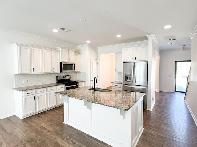 kitchen featuring dark hardwood / wood-style flooring, appliances with stainless steel finishes, white cabinetry, a kitchen island with sink, and sink