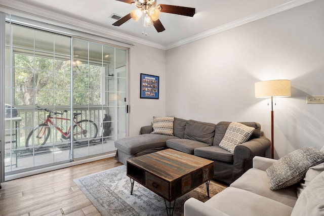 living area featuring a ceiling fan, visible vents, ornamental molding, and wood finished floors